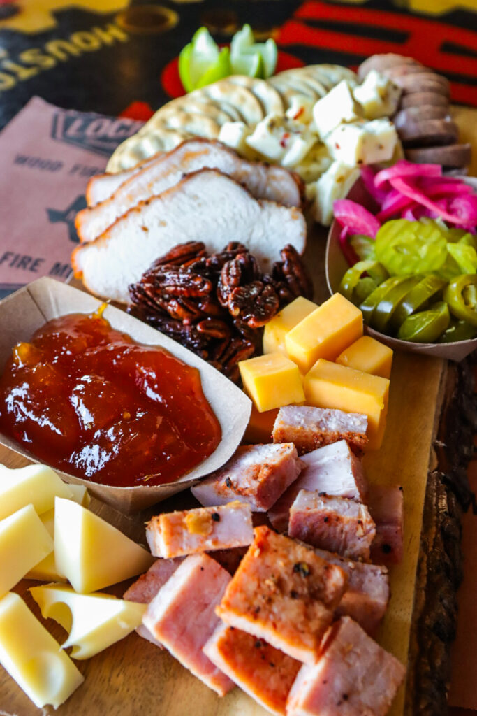 a view of an assortment of bbq meats, cheeses and spreads - laid out in a beautifully decorative fashion.