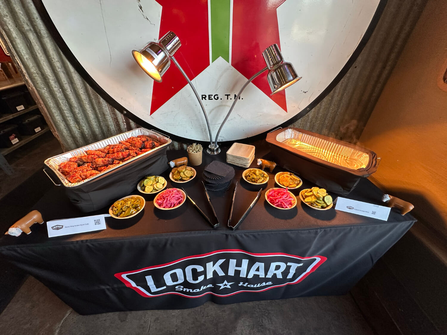 Buffet table with smoked meats, pickles, onions, and sides in aluminum chafing dishes at Lockhart Smokehouse event.